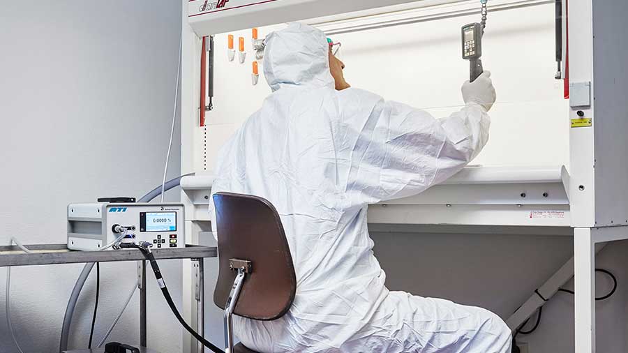 Man in lab coat measuring air in a cabinet